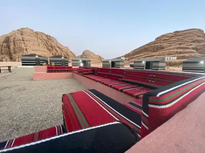 a row of red benches with mountains in the background at مخيم الجبال البرونزية in Wadi Rum