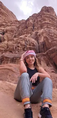 a girl sitting on the ground in the desert at مخيم الجبال البرونزية in Wadi Rum