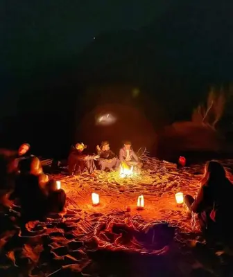 a group of people sitting around a fire with candles at Wateen Home in Wadi Musa