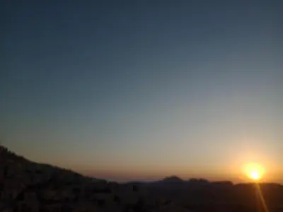 a sunset in the mountains with the sun setting at Wateen Home in Wadi Musa