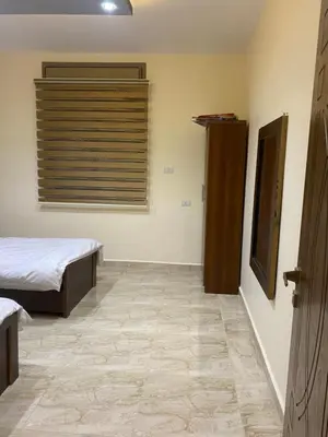 a bedroom with two beds and a window and a tiled floor at Darkum Apartment in Wadi Musa