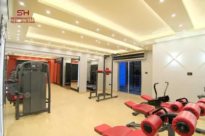 a gym with red cardio equipment in a room at Sedrah Hotel in Irbid