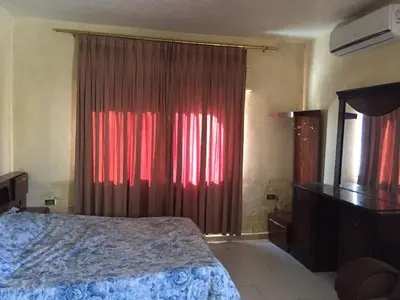 a bedroom with a bed and a window with red curtains at PALM Home in Amman