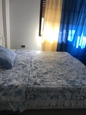 a bed in a bedroom with a blue curtain at PALM Home in Amman