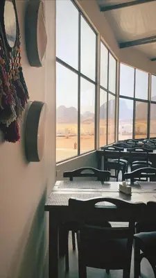 a row of tables and chairs in a room with windows at Zeina Desert Lodge in Wadi Rum
