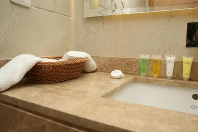 a bathroom counter with a sink and towels and a basket at Gloria Hotel Amman in Amman