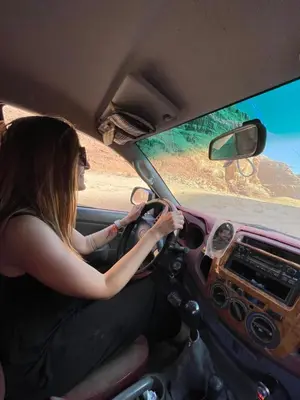 a woman driving a car while looking out the window at Zarb Desert Camp in Wadi Rum