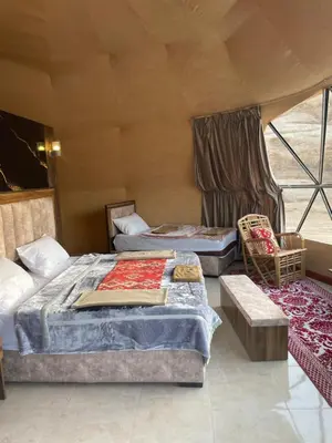 a room with two beds and a chair in a tent at Zarb Desert Camp in Wadi Rum
