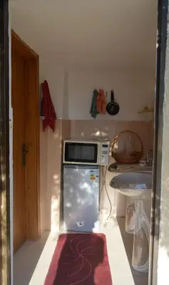 a small kitchen with a refrigerator with a microwave at Our Villa's Pine Cottage - HQ Budget Stay - Wonderful horizon view of Jerash in Jerash