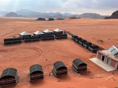 a group of beds in the middle of the desert at Candle light camp & tours in Wadi Rum
