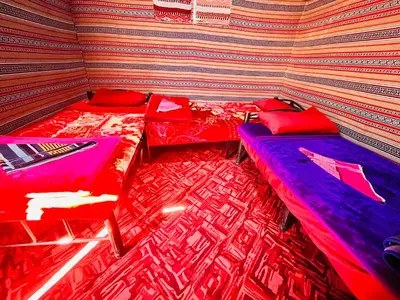 two beds in a room with red and purple at Wadi Rum Bedouin Heart in Wadi Rum