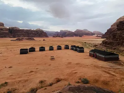 a group of tents in a desert with rocks at Wadi Rum Bedouin Heart in Wadi Rum