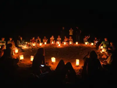 a group of people sitting in the sand with candles at Sand Star Camp in Wadi Rum
