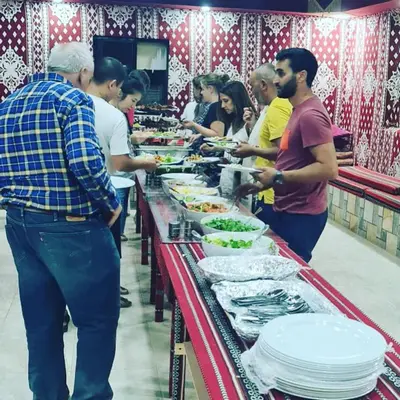 a group of people standing at a buffet line with food at Sand Star Camp in Wadi Rum