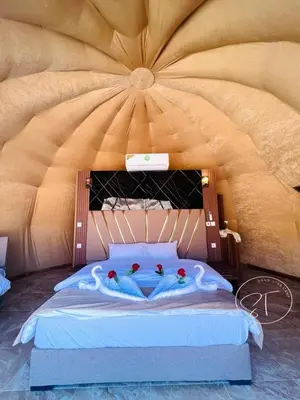 a bedroom with a large bed with two people in it at Sand Star Camp in Wadi Rum
