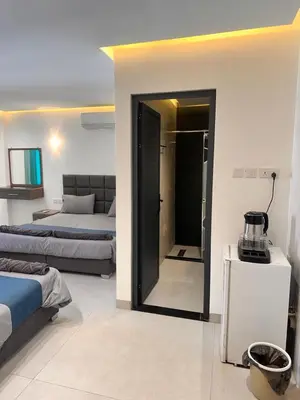 a hotel room with two beds and a door to a bedroom at ArwaHotel Apartments اروى للشقق الفندقية in Aqaba