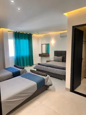 a room with three beds in a room with blue curtains at ArwaHotel Apartments اروى للشقق الفندقية in Aqaba