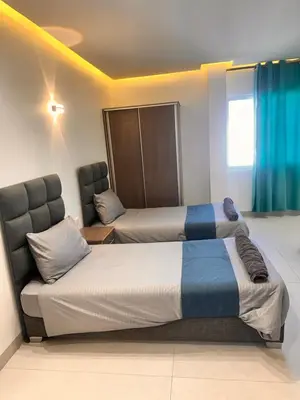 a room with two beds and a chair in it at ArwaHotel Apartments اروى للشقق الفندقية in Aqaba