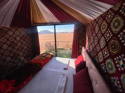 a room with a couch and a view of the desert at Desert shine camp in Wadi Rum