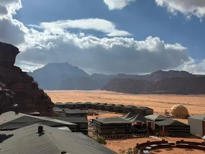 a view of a desert with buildings and mountains at Faisal Wadi Rum Camp in Wadi Rum