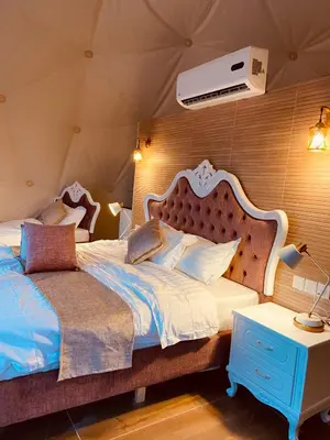 a bedroom with a large bed with a white headboard at Faisal Wadi Rum Camp in Wadi Rum