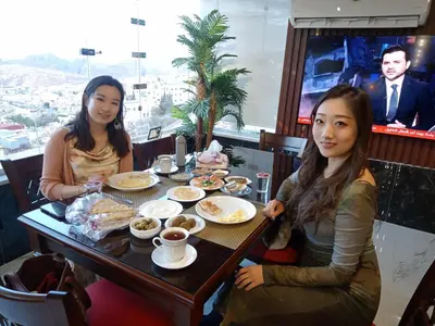 two women sitting at a table eating food at Petra Monastery Tourist Hotel in Wadi Musa
