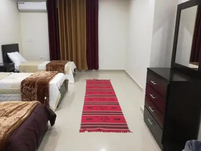 a hotel room with two beds and a red rug at Petra Monastery Tourist Hotel in Wadi Musa