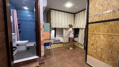 a woman standing in a room with a hospital room at Carob Hostel in Amman