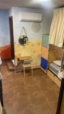 a room with a table and a bed and a desk at Carob Hostel in Amman