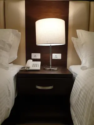 a lamp and a phone on a nightstand between two beds at Petra Heart Hotel in Wadi Musa