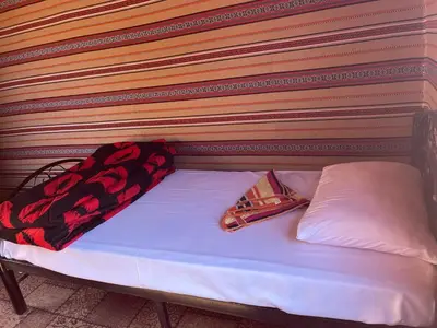 a bed with a headboard with a pillow and a tie at Quite bedouin life in Wadi Rum