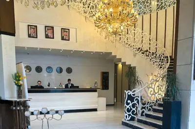 a lobby with a chandelier and people in a building at Opal Hotel Amman in Amman