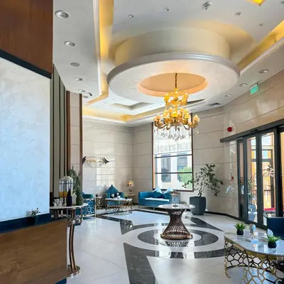 a lobby with a chandelier and tables and chairs at Opal Hotel Amman in Amman