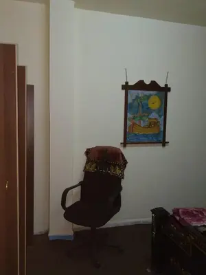 a chair in a room with a painting on the wall at Jarajreh Apartments/ Hotel in Kerak