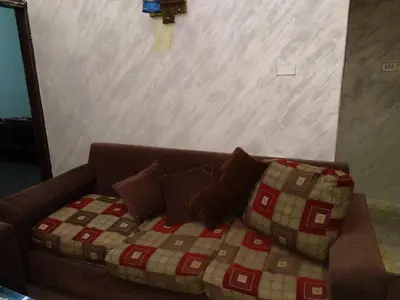 a brown couch with pillows in a living room at Jarajreh Apartments/ Hotel in Kerak