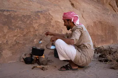 a man is cooking over a pot over a fire at Walid Bedouin Camp in Wadi Rum