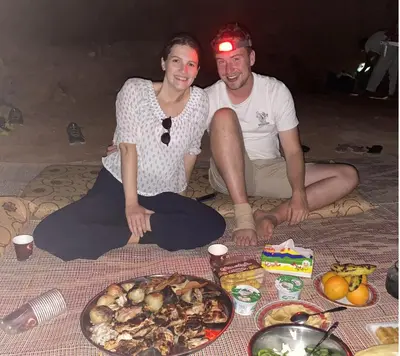 a man and woman sitting on the floor with a plate of food at Walid Bedouin Camp in Wadi Rum