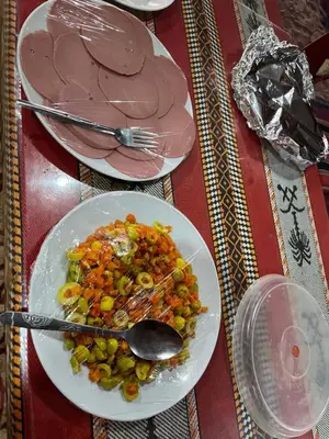 a table with two plates of food and a spoon at Walid Bedouin Camp in Wadi Rum