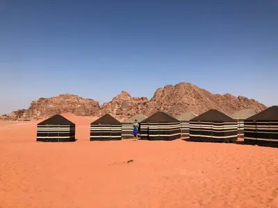 a person standing in front of a row of huts in the desert at Wadi rum desert breath in Wadi Rum