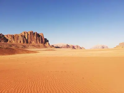 a desert with rocks and sand in the foreground at Wadi rum desert breath in Wadi Rum