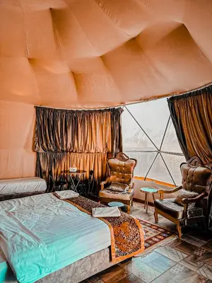 a bedroom with a bed and a chair and a window at Rum warm bubble camp in Wadi Rum