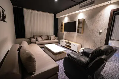 a living room with a couch and chairs and a tv at Diamond Hotel in Amman