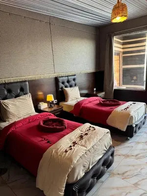 two beds in a hotel room with red sheets at Sharah Luxury Camp in Wadi Rum