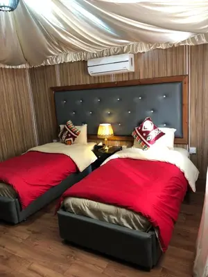 two beds in a bedroom with red sheets at Sharah Luxury Camp in Wadi Rum