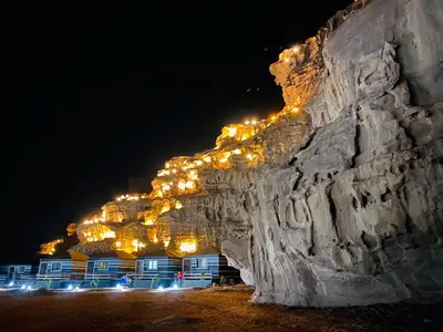 a rock wall with lights on it at night at Sharah Luxury Camp in Wadi Rum