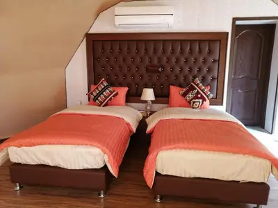two beds with red pillows in a bedroom at Sharah Luxury Camp in Wadi Rum