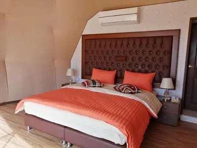 a bedroom with a large bed with orange pillows at Sharah Luxury Camp in Wadi Rum