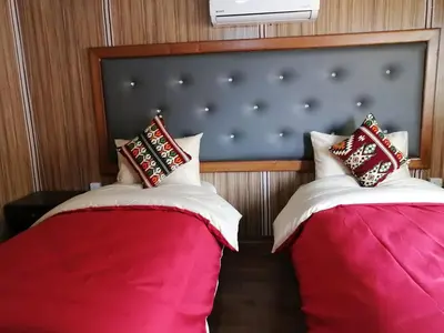 two beds in a room with red and white pillows at Sharah Luxury Camp in Wadi Rum