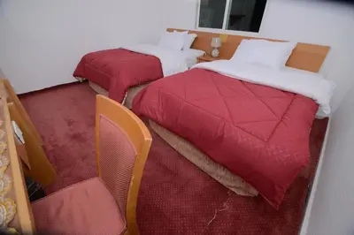 two beds in a hotel room with red sheets at Petra Lion Hotel in Wadi Musa