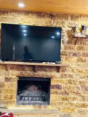 a television on top of a brick fireplace at شقق الياسمين in Jerash